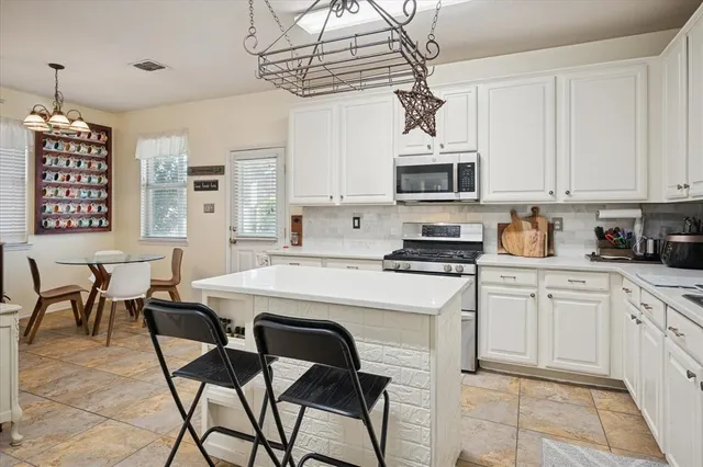 a kitchen with stainless steel appliances granite countertop a sink dishwasher a stove a refrigerator with a dining table and chairs