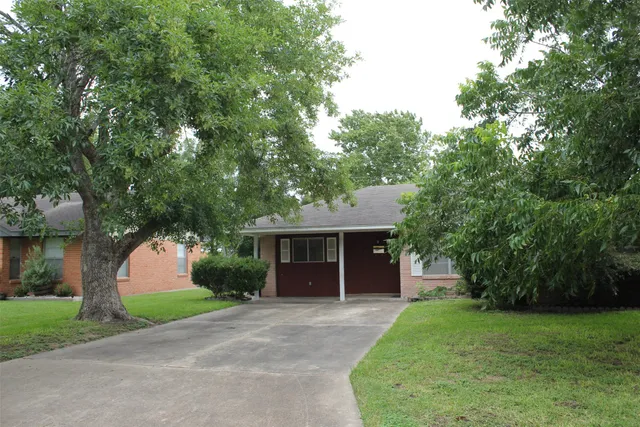 a front view of a house with a garden and trees