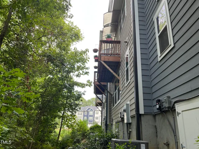 a front view of a building with a garden and trees