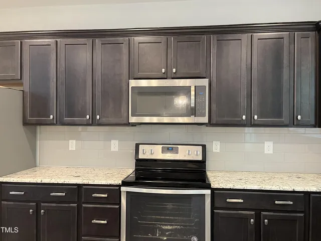 a kitchen with granite countertop a stove and a microwave