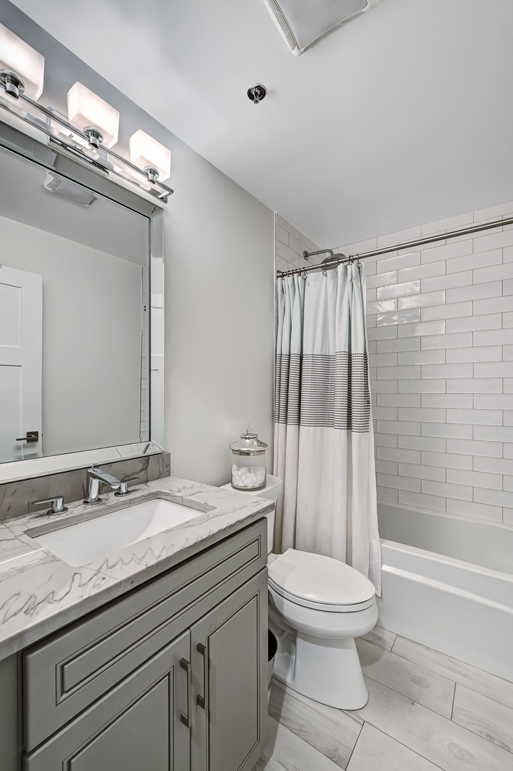 1140 Old Mill Road, Unit 101F Hinsdale, IL 60521 - Photo 12 of 14 a bathroom with a granite countertop sink a toilet a mirror and shower