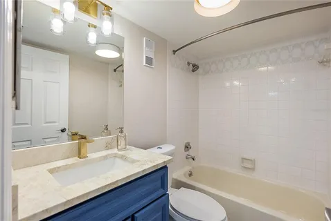a bathroom with a granite countertop sink a toilet a mirror and shower