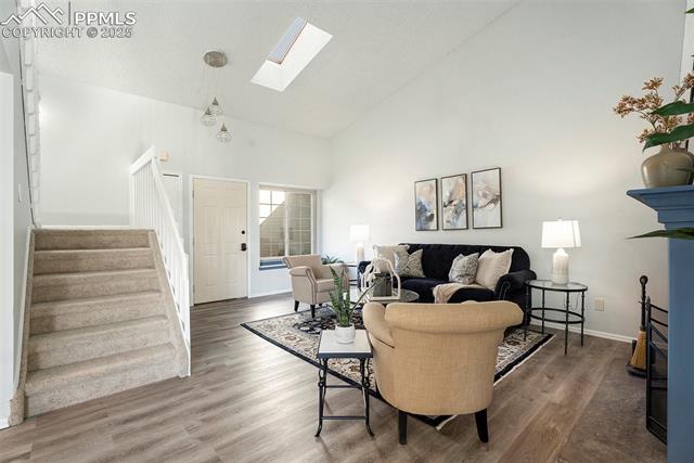 86 Rising Sun Terrace Colorado Springs, CO 80921 - Photo 7 of 36 Living area featuring a skylight, stairs, high vaulted ceiling, vinyl floors, and a fireplace