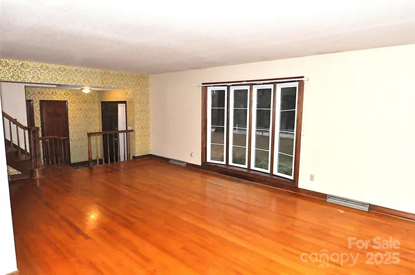 a view of an empty room with chandelier and glass door