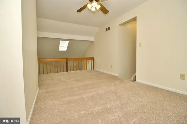 an empty room with ceiling fan and window