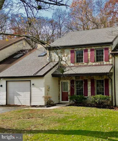 a view of a brick house with a yard plants and large tree