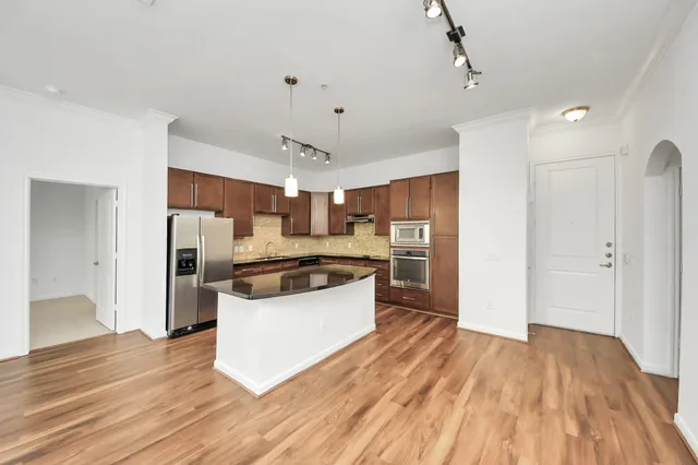 a large kitchen with a wooden floor and stainless steel appliances