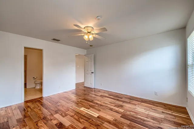 a view of empty room with wooden floor and ceiling fan