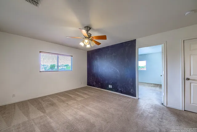 an empty room with a fan & a window