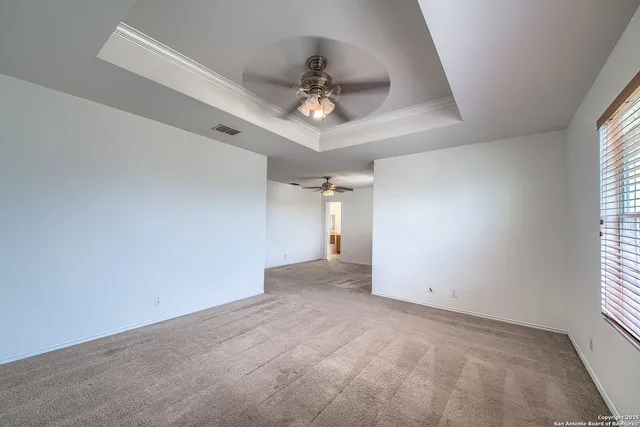 an empty room with chandelier fan and windows