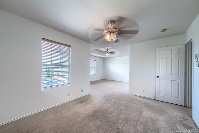 an empty room with a window and a ceiling fan