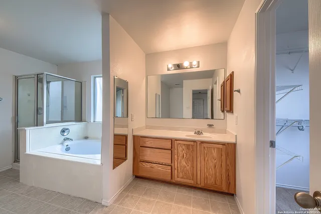 a bathroom with a double vanity sink mirror and bathtub