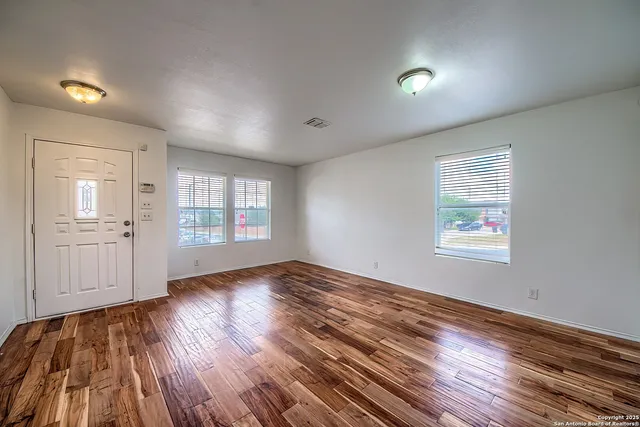 an empty room with wooden floor and windows