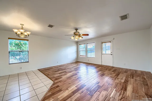 a view of an empty room and window and chandelier fan