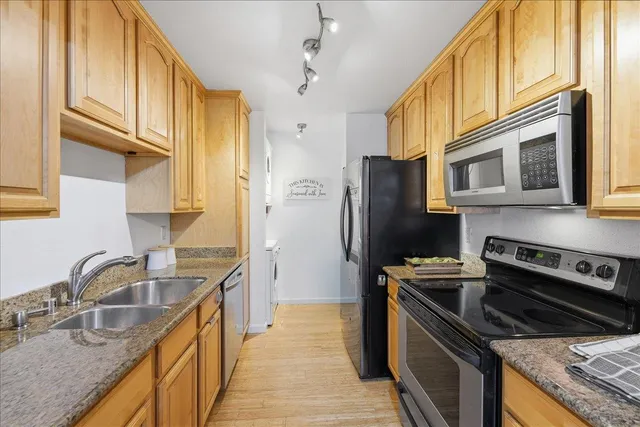 a kitchen with stainless steel appliances granite countertop a sink stove and refrigerator