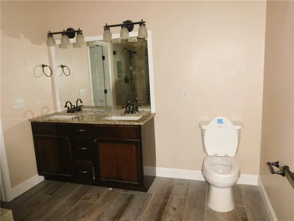 a bathroom with a granite countertop toilet a sink and a mirror