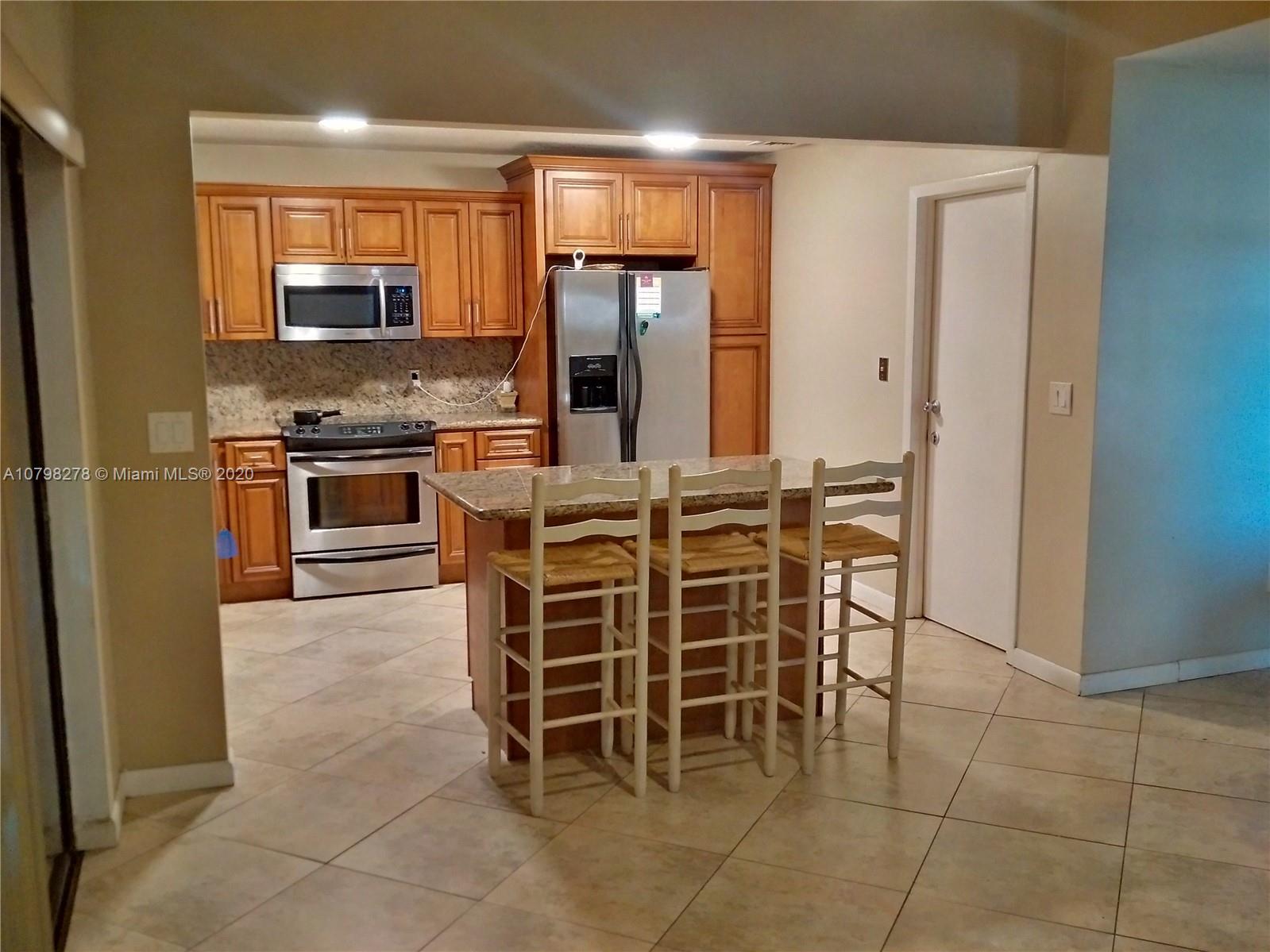 13060 Southwest 263rd Terrace Homestead, FL 33032 - Photo 4 of 28 a kitchen with stainless steel appliances granite countertop a stove top oven a sink a dining table and chairs
