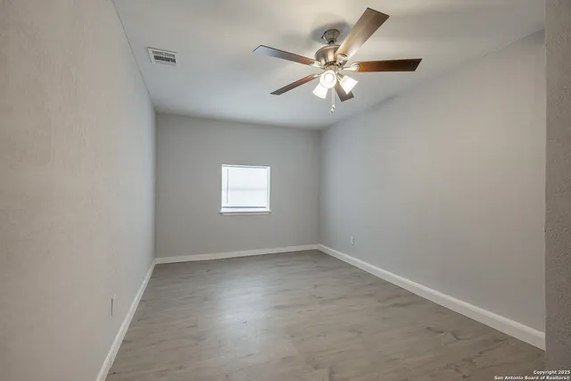 an empty room with a chandelier fan and windows