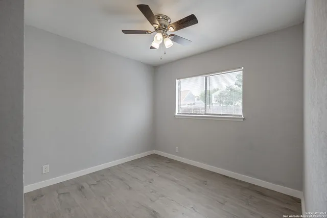 an empty room with a window and a ceiling fan