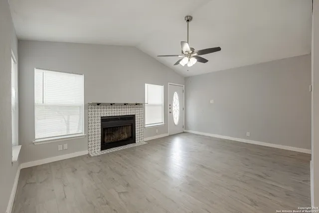 an empty room with chandelier fan and windows