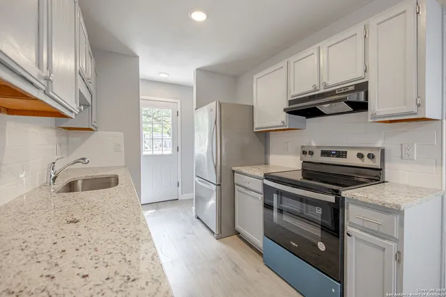 a kitchen with stainless steel appliances granite countertop a refrigerator stove and sink