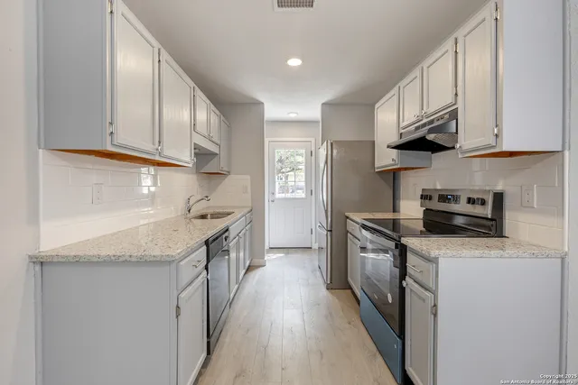 a kitchen with stainless steel appliances granite countertop a sink a stove and cabinets