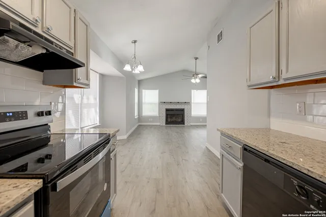 a kitchen with stainless steel appliances granite countertop a sink a stove and a wooden floors