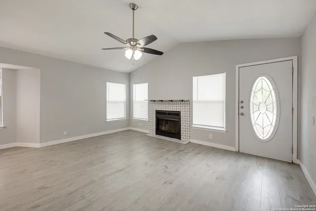 an empty room with wooden floor fireplace and window