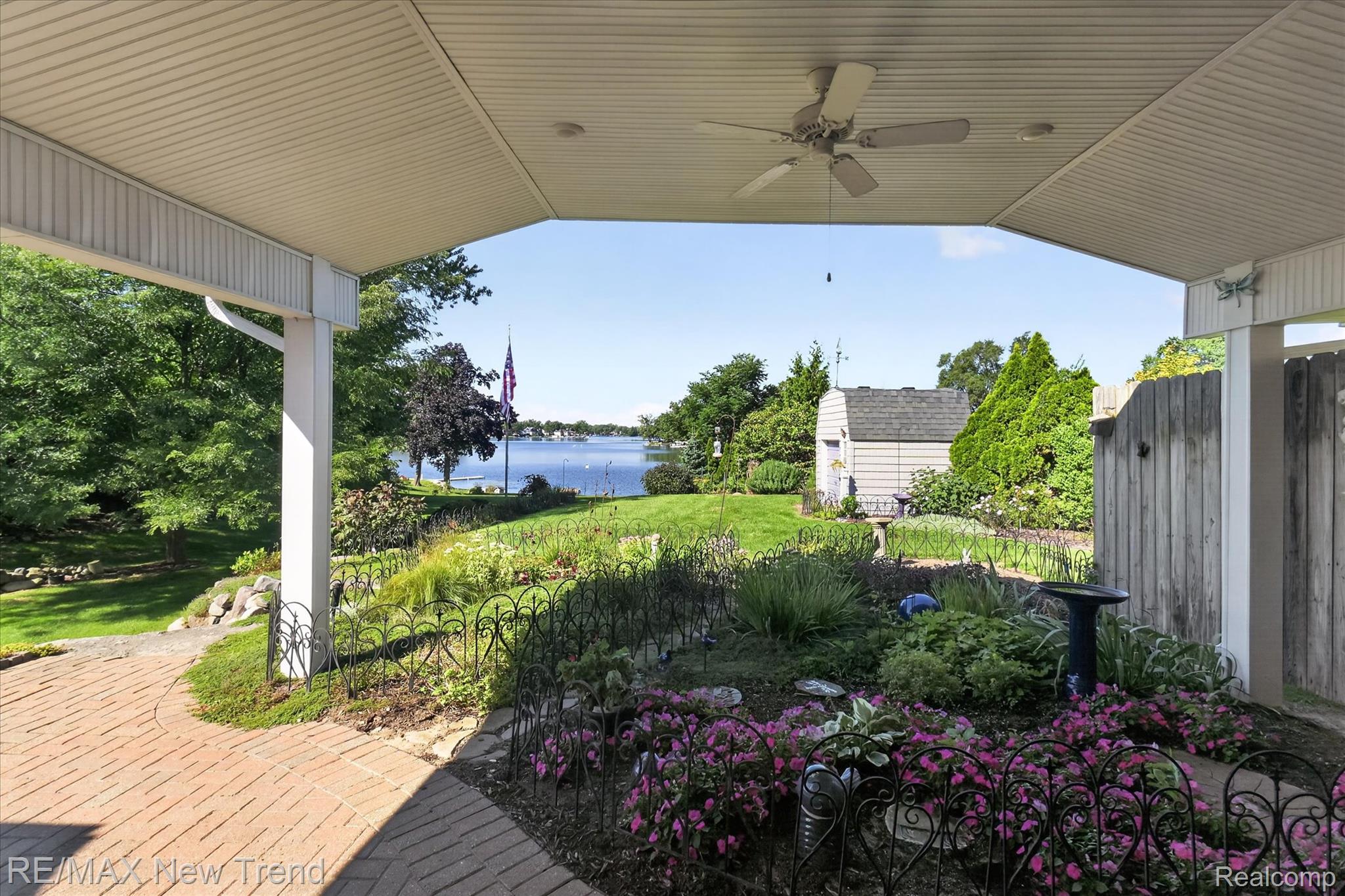 2529 South Commerce Road Walled Lake, MI 48390 - Photo 51 of 66 Covered patio with a ceiling fan, brick paver patio, established garden beds, and a lake backdrop