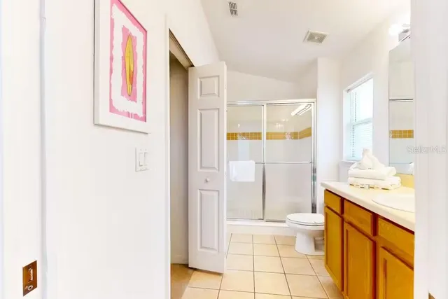 a bathroom with a granite countertop sink a toilet a mirror and shower