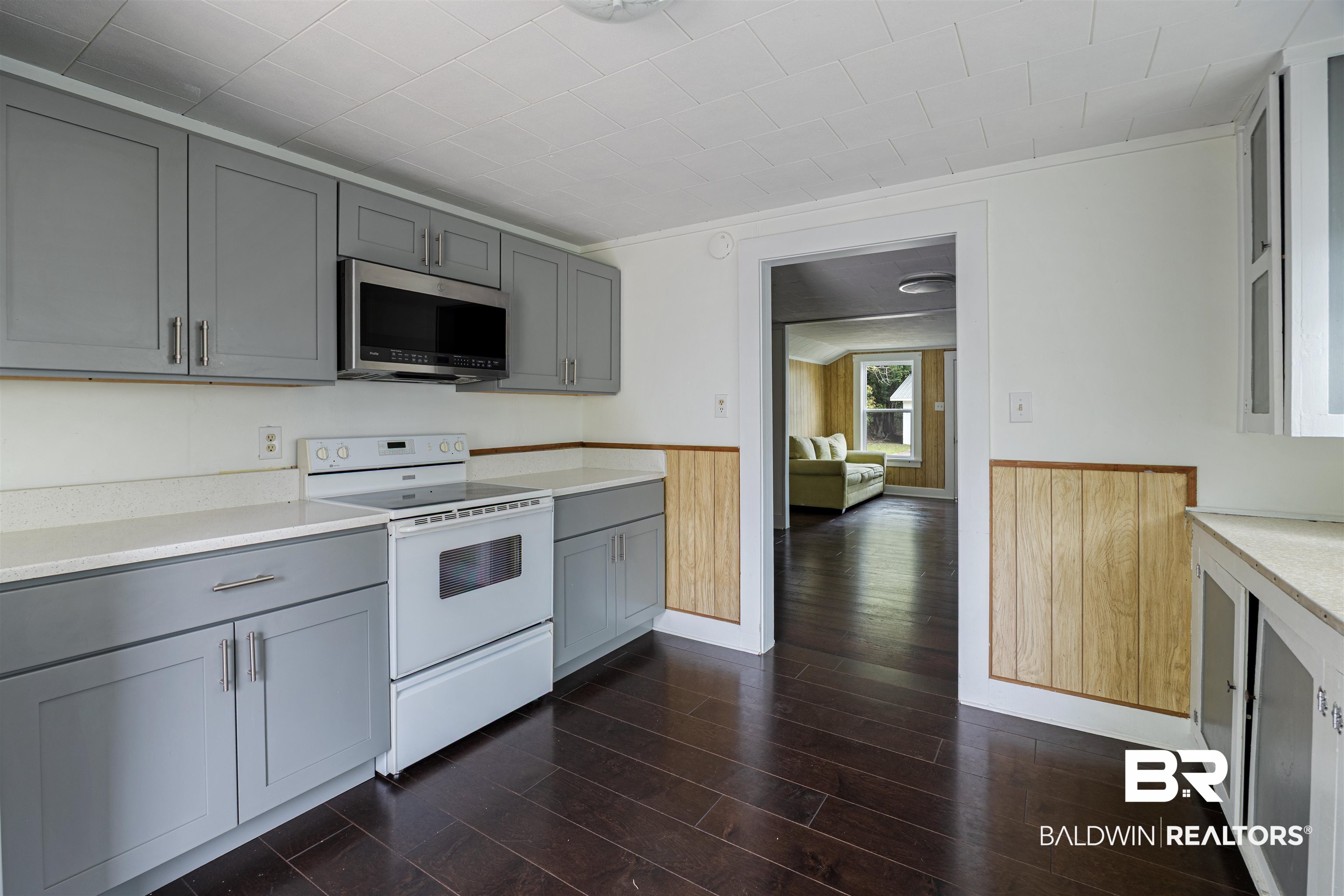 112 South Juniper Street Foley, AL 36535 - Photo 22 of 64 Kitchen with gray cabinets, a wainscoted wall, white electric stove, stainless steel microwave, and dark wood finished floors