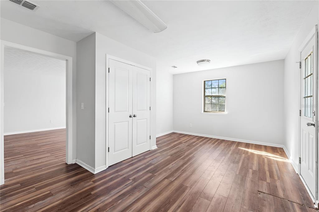 17380 Northwest Green Acres Road Bristol, FL 32321 - Photo 13 of 35 an empty room with wooden floor and windows