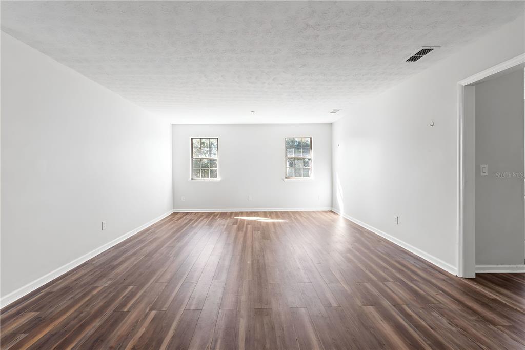 17380 Northwest Green Acres Road Bristol, FL 32321 - Photo 7 of 35 an empty room with wooden floor and windows