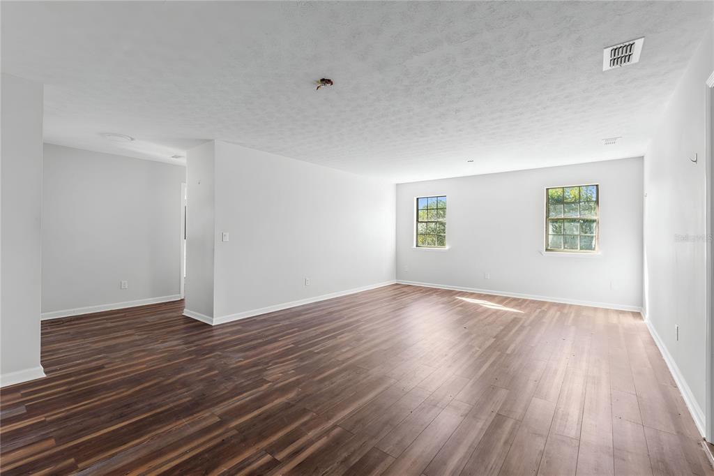 17380 Northwest Green Acres Road Bristol, FL 32321 - Photo 9 of 35 an empty room with wooden floor and windows