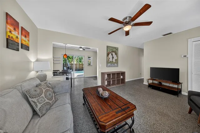 a living room with furniture a flat screen tv and a ceiling fan