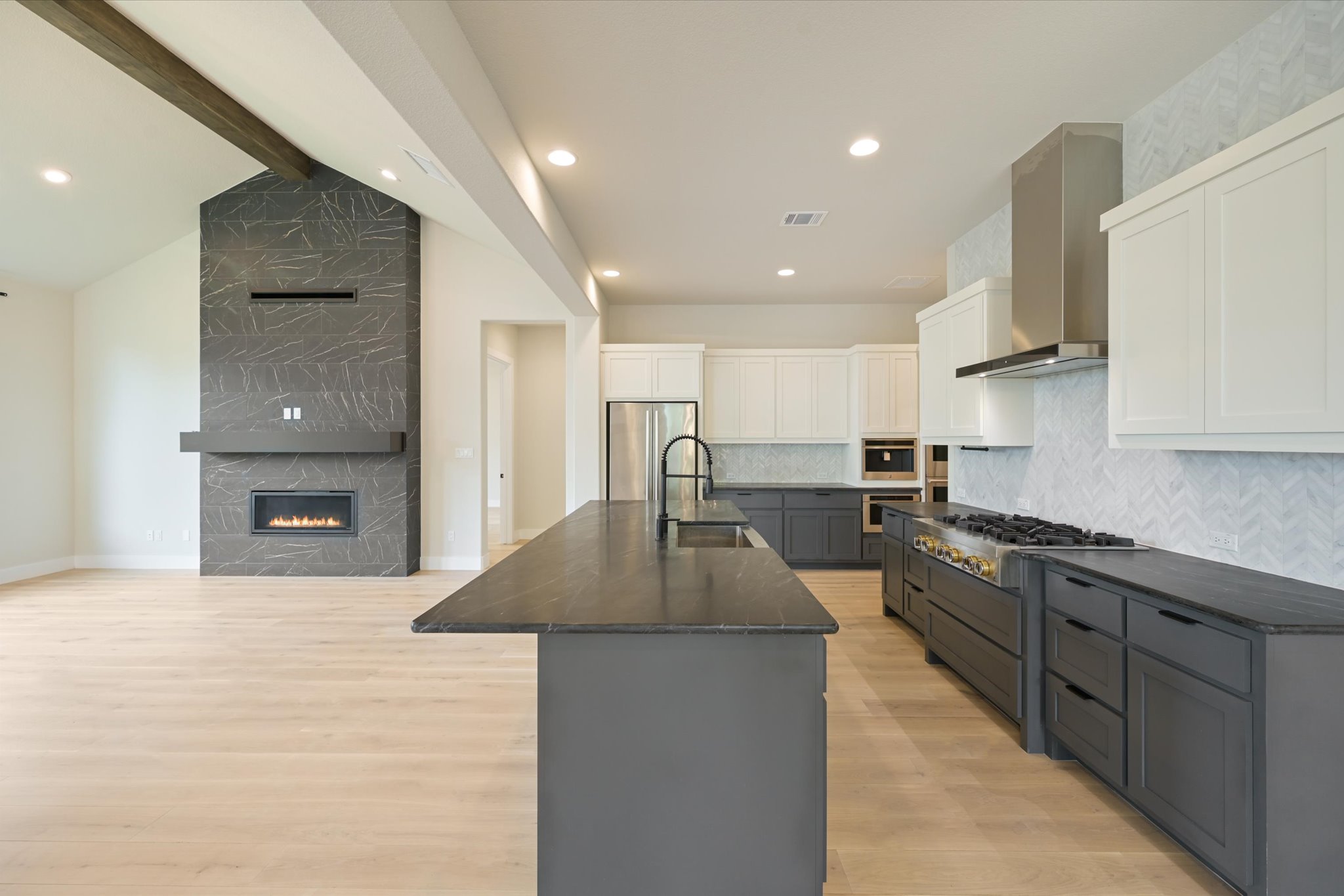 913 Presa Arriba Road Austin, TX 78733 - Photo 10 of 30 A spacious, open-concept living area features a grand fireplace and a chef-ready kitchen.