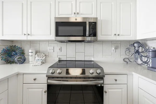 a kitchen with stainless steel appliances granite countertop white cabinets a stove top oven