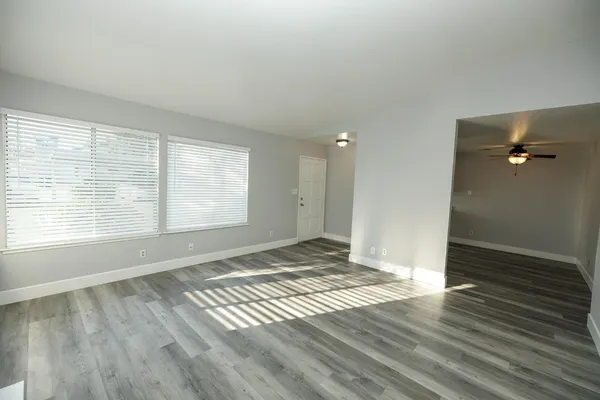 an empty room with wooden floor and windows