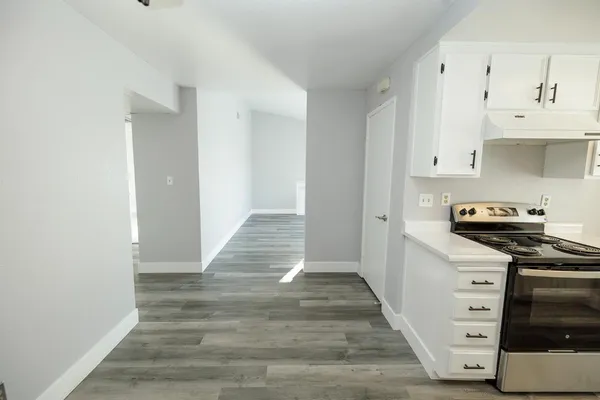 a kitchen with wooden floor and cabinets