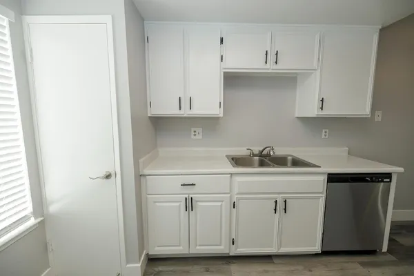 a kitchen with white cabinets and sink