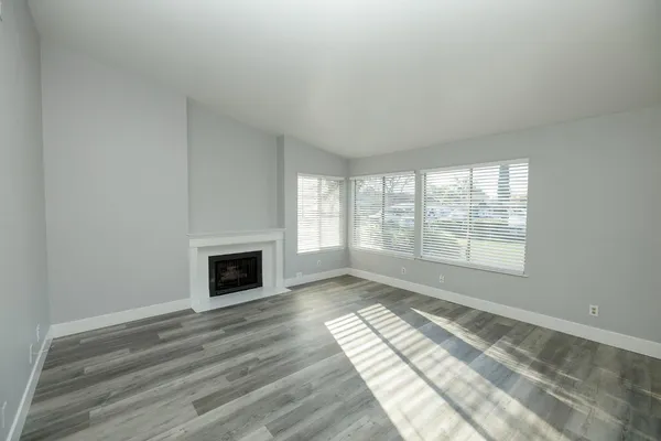 a view of empty room with wooden floor and fireplace