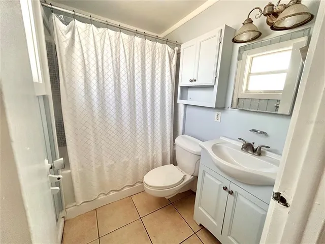 a bathroom with a sink a toilet a window and shower