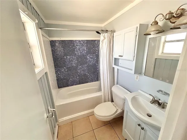 a bathroom with a bathtub shower sink vanity mirror and toilet