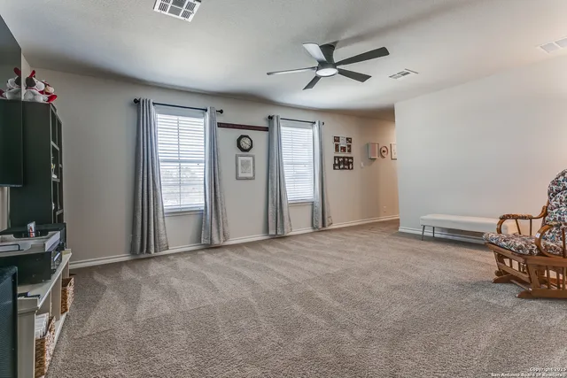 an empty room with windows and ceiling fan