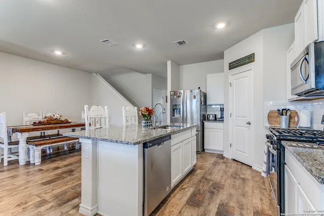 a kitchen with stainless steel appliances granite countertop a refrigerator and a stove top oven