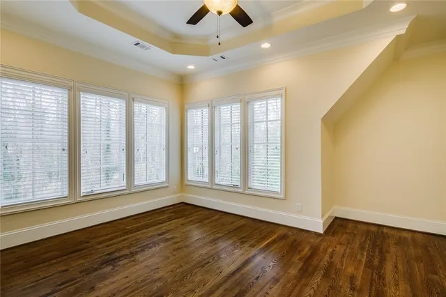 a view of an empty room with window and chandelier fan