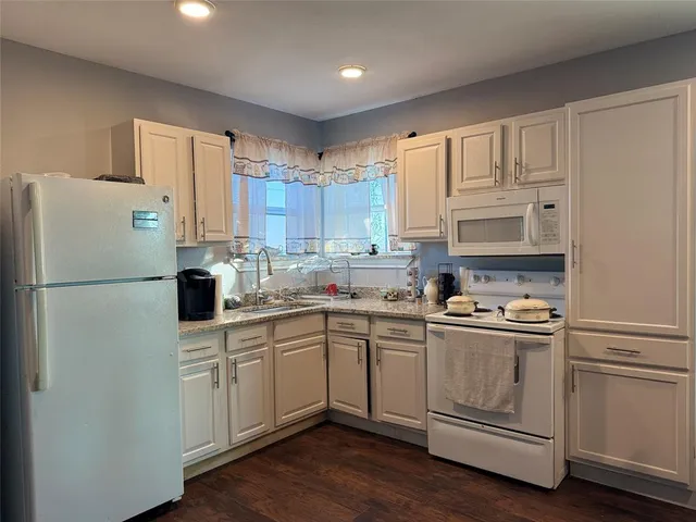 a kitchen with white cabinets and white appliances
