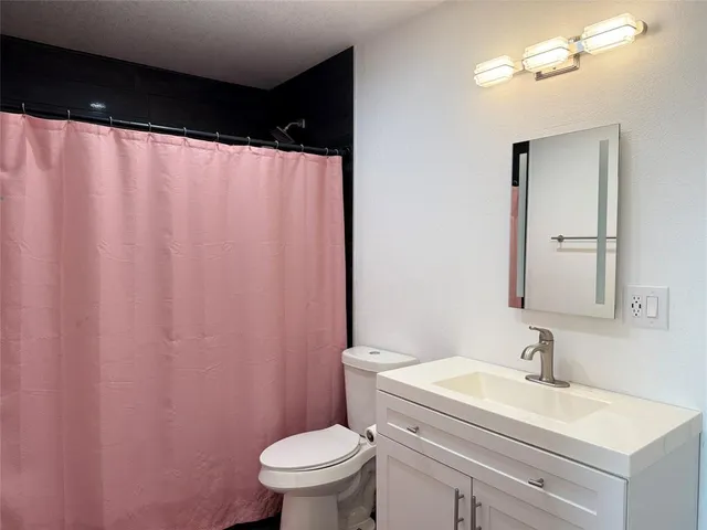 a bathroom with a sink a toilet and shower curtain