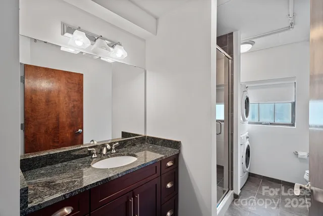 a bathroom with a granite countertop sink a mirror and shower view