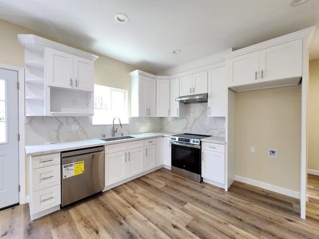 a kitchen with granite countertop white cabinets and stainless steel appliances